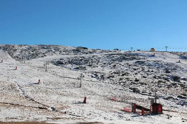 Padre João Maximino Fragoso junto a um Volkswagen Carocha branco na Serra da Estrela.