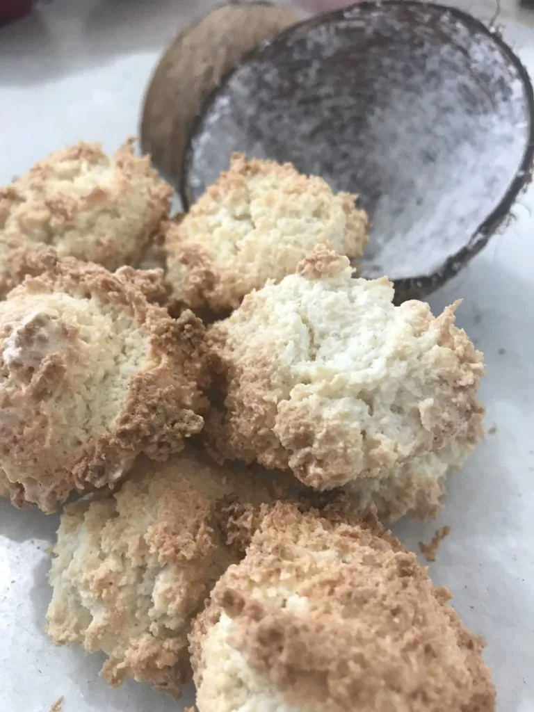 Macaroons ingleses dourados dispostos em uma assadeira, com textura de coco ralado visível.