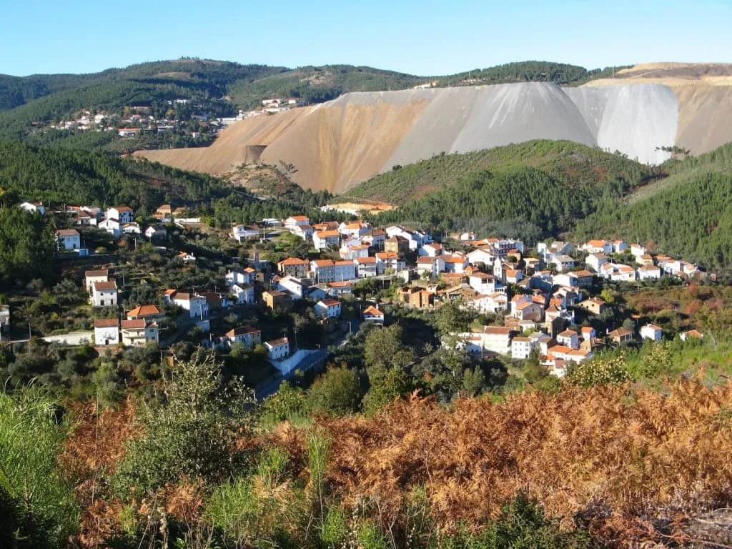 Interior de uma barbearia com decoração temática sobre as Minas da Panasqueira, incluindo minerais, fotografias históricas e uma águia do Benfica.