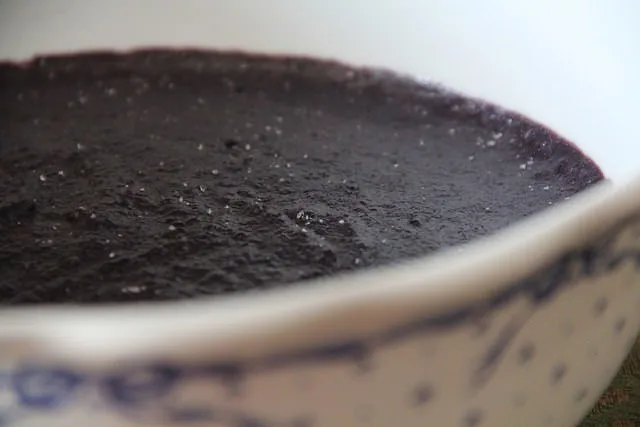 Taça de gelado artesanal de amora silvestre decorada com amoras frescas num ambiente de verão.