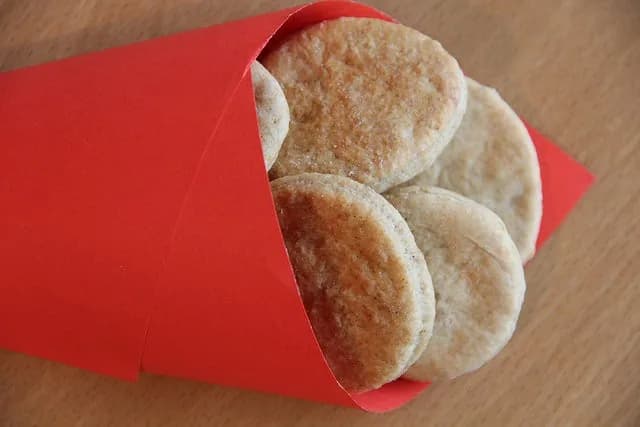 Bolachas caseiras de gengibre e canela recortadas em formatos diversos dispostas sobre um tabuleiro com papel vegetal.