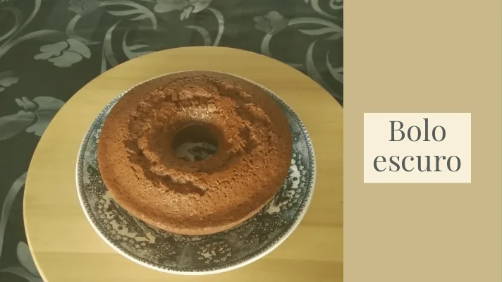 Um delicioso bolo escuro caseiro da Cogula, com textura fofa e aroma a canela, servido para um lanche em família.