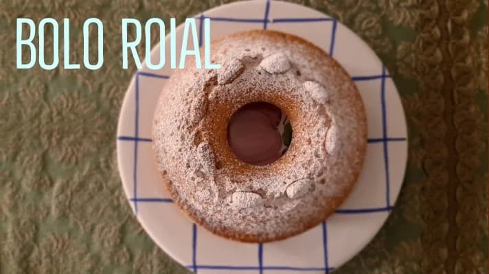 Bolo Roial caseiro acabado de cozer, decorado com pedaços de nozes e amêndoas, polvilhado com açúcar.