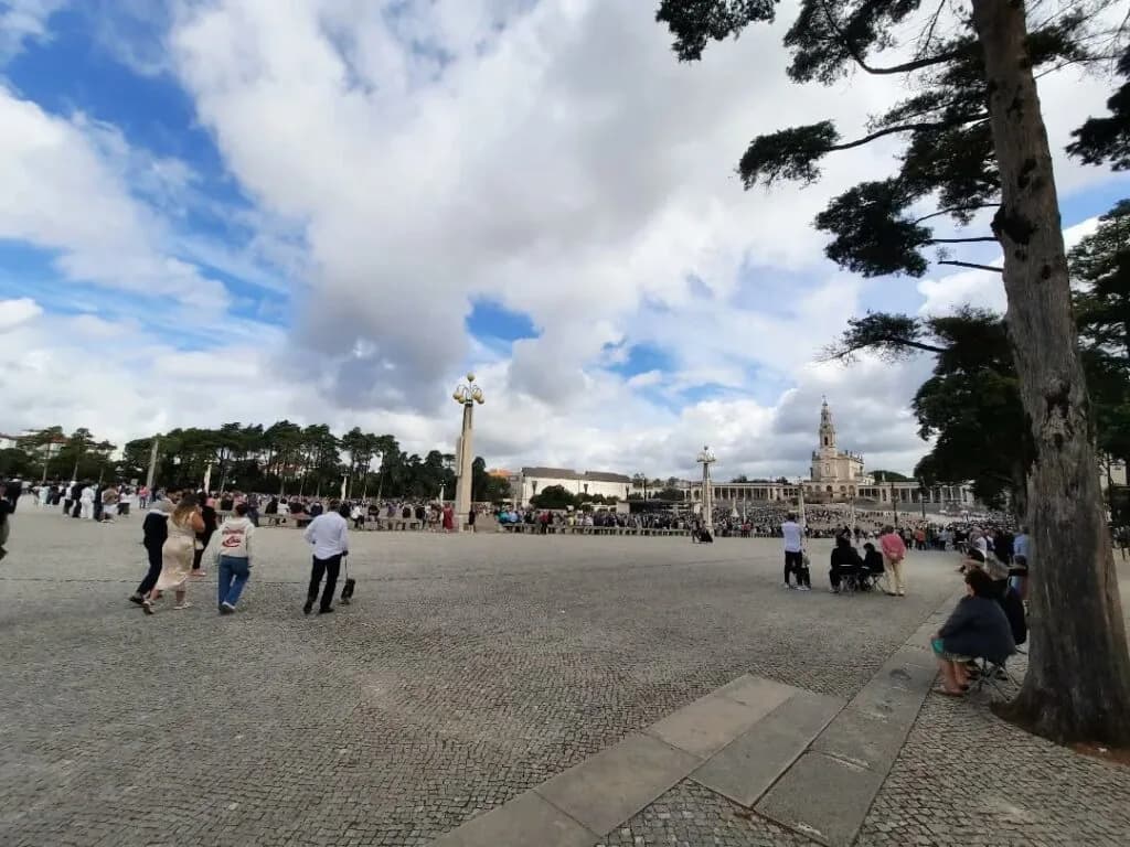 Fiéis reunidos no Santuário de Fátima em oração e serviço humilde durante uma celebração religiosa.